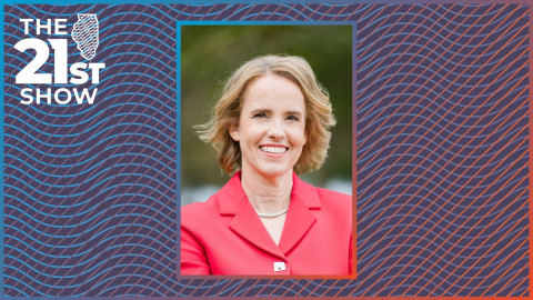 a white woman with blond hair wears a coral coat