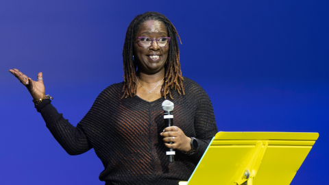 Woman stands on stage holding microphone 