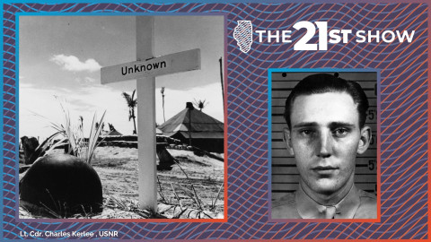 A world war 2 military helmet on a sandy beach next to a white cross marking a grave. The cross is labeled 